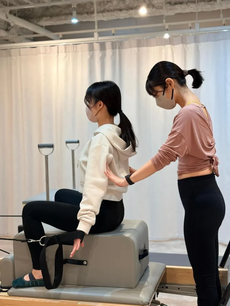 チェアに座ったお客様の背中に、トレーナーが手を添えて姿勢を確認している様子