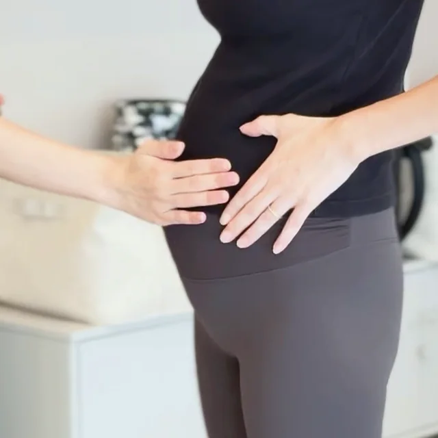 妊娠中のお客様のお腹に、トレーナーがそっと手を添えている様子