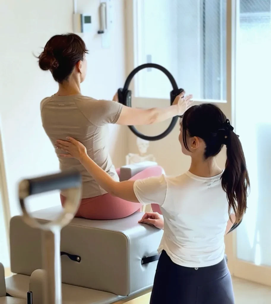 リングを使ったエクササイズで、トレーナーがお客様の背中を支えている様子