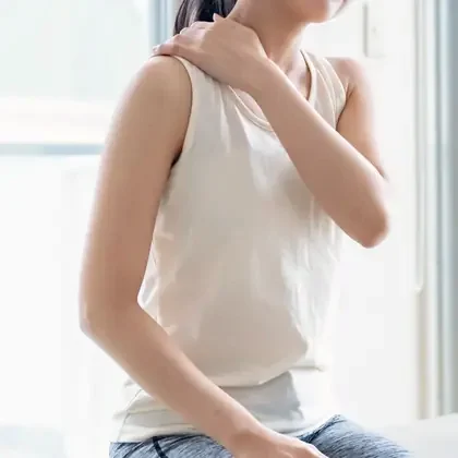 肩に手を当て、肩と首のこりを気にする女性